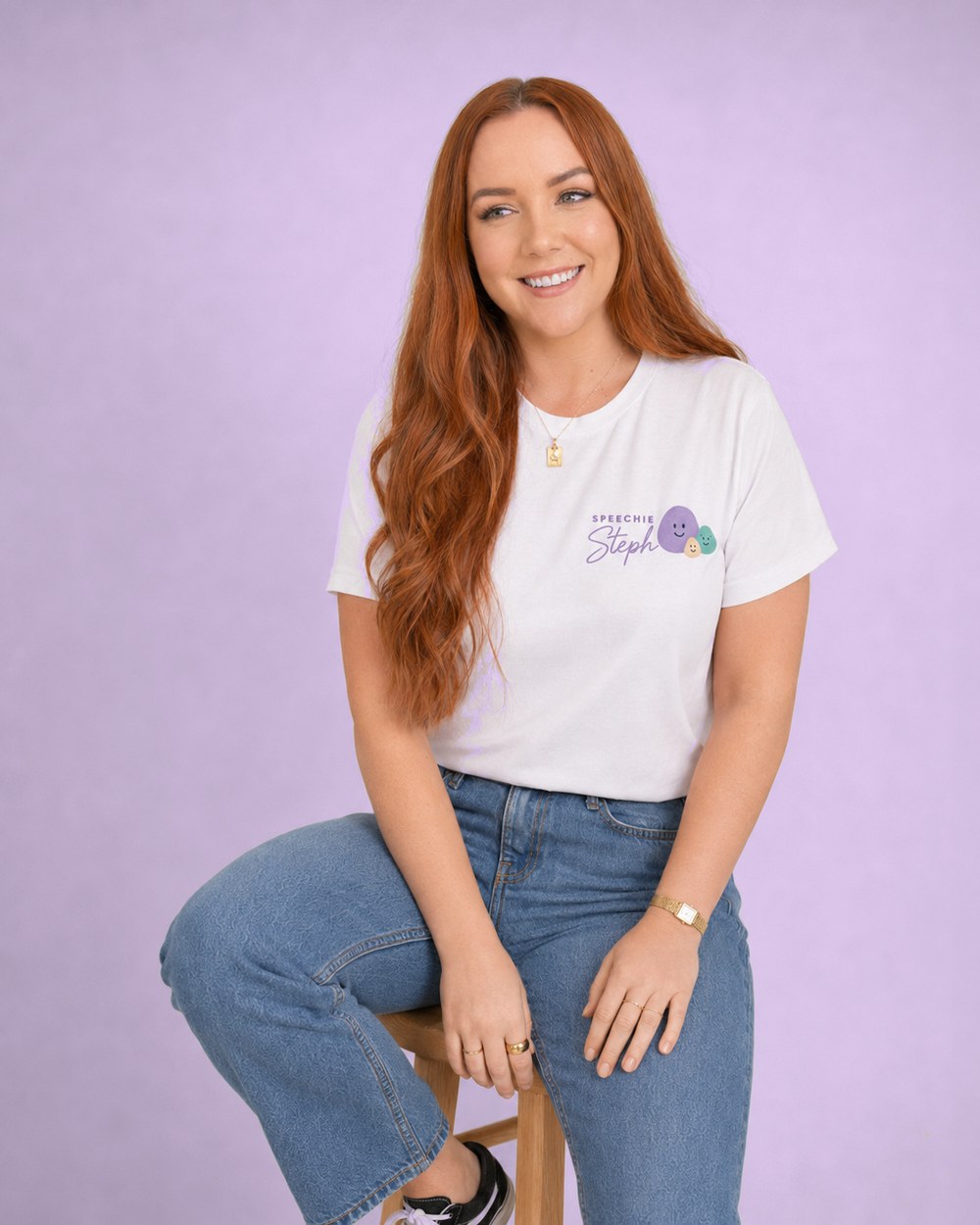 Steph, paediatric speech pathologist, sitting on a stool and smiling, wearing a Speechie Steph t-shirt